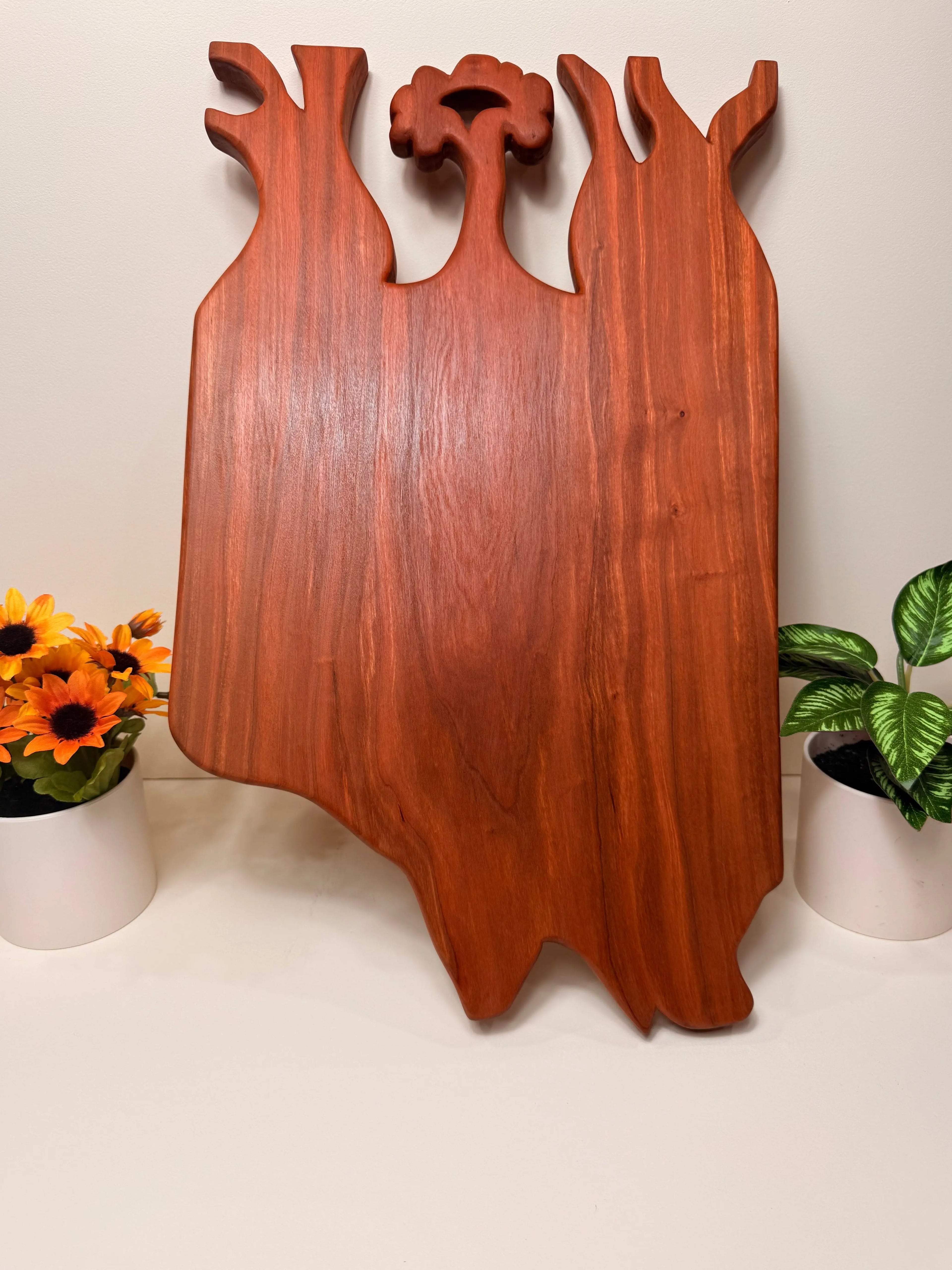 Hand-carved cherry wood charcuterie board with tree cutout handles, upright
