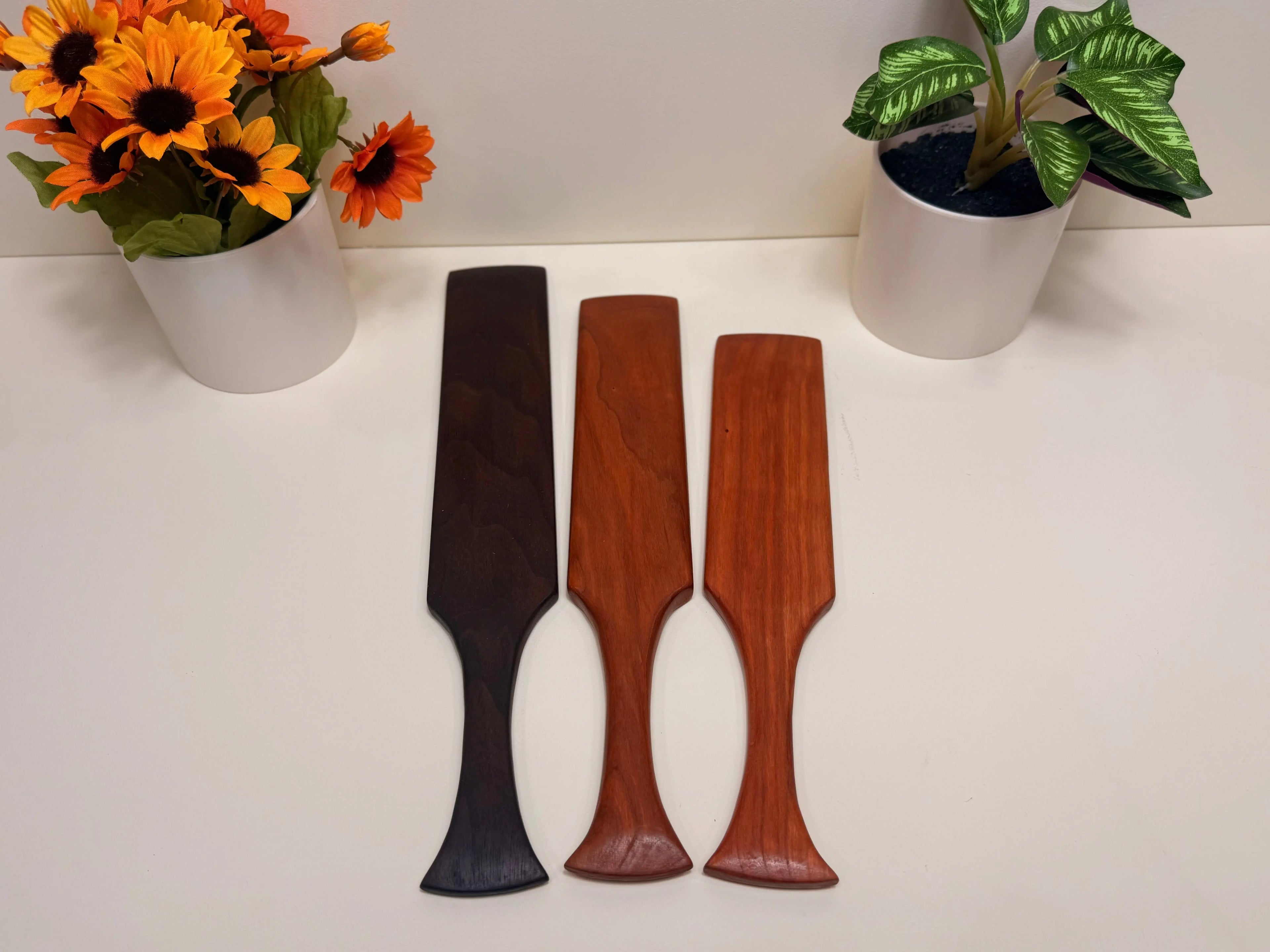 Hardwood kitchen spurtles in three wood tones: dark walnut and reddish cherry.