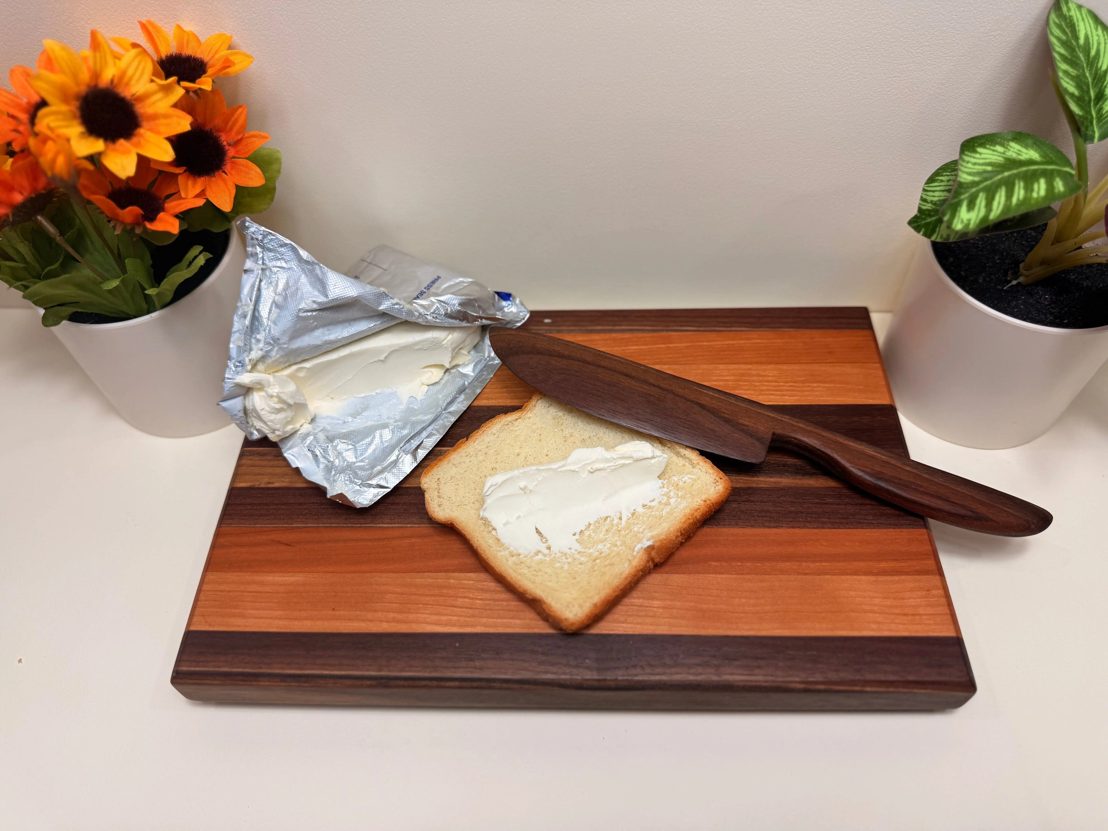 Wood butter spreader with tapered handle resting on a charcuterie board