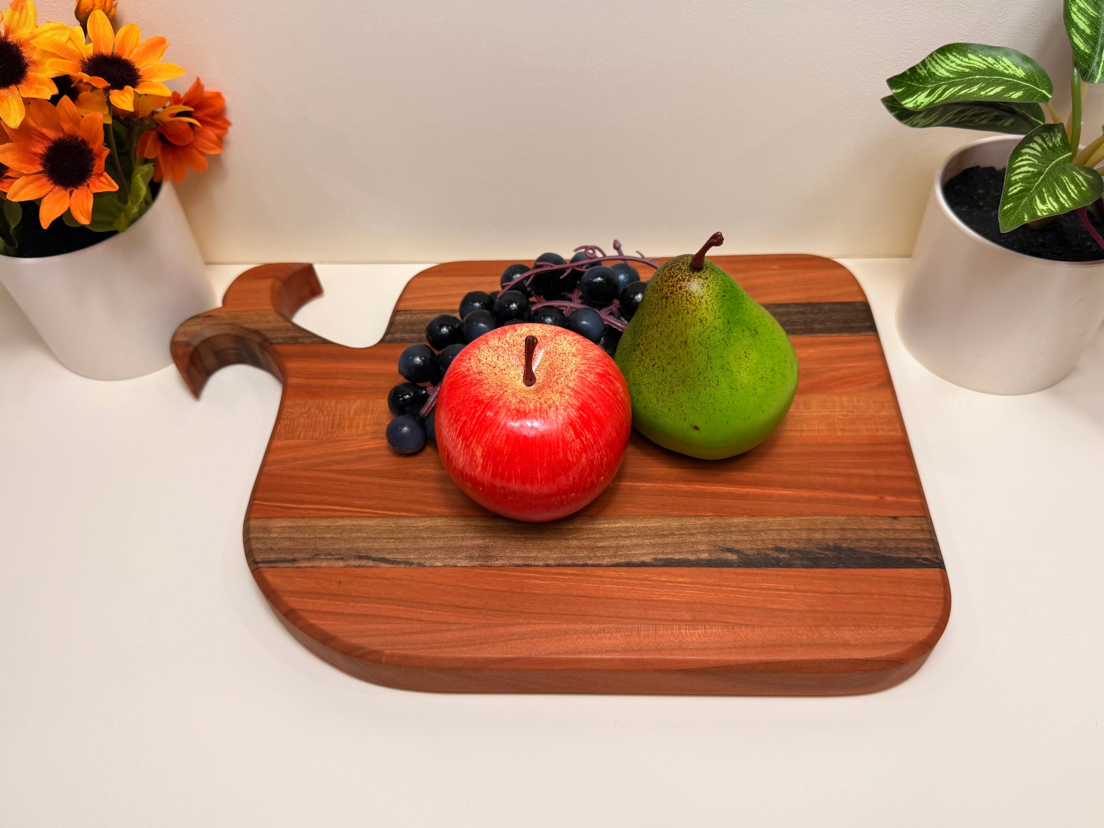 Whale-shaped wooden serving board with handle, holding fruit and grapes