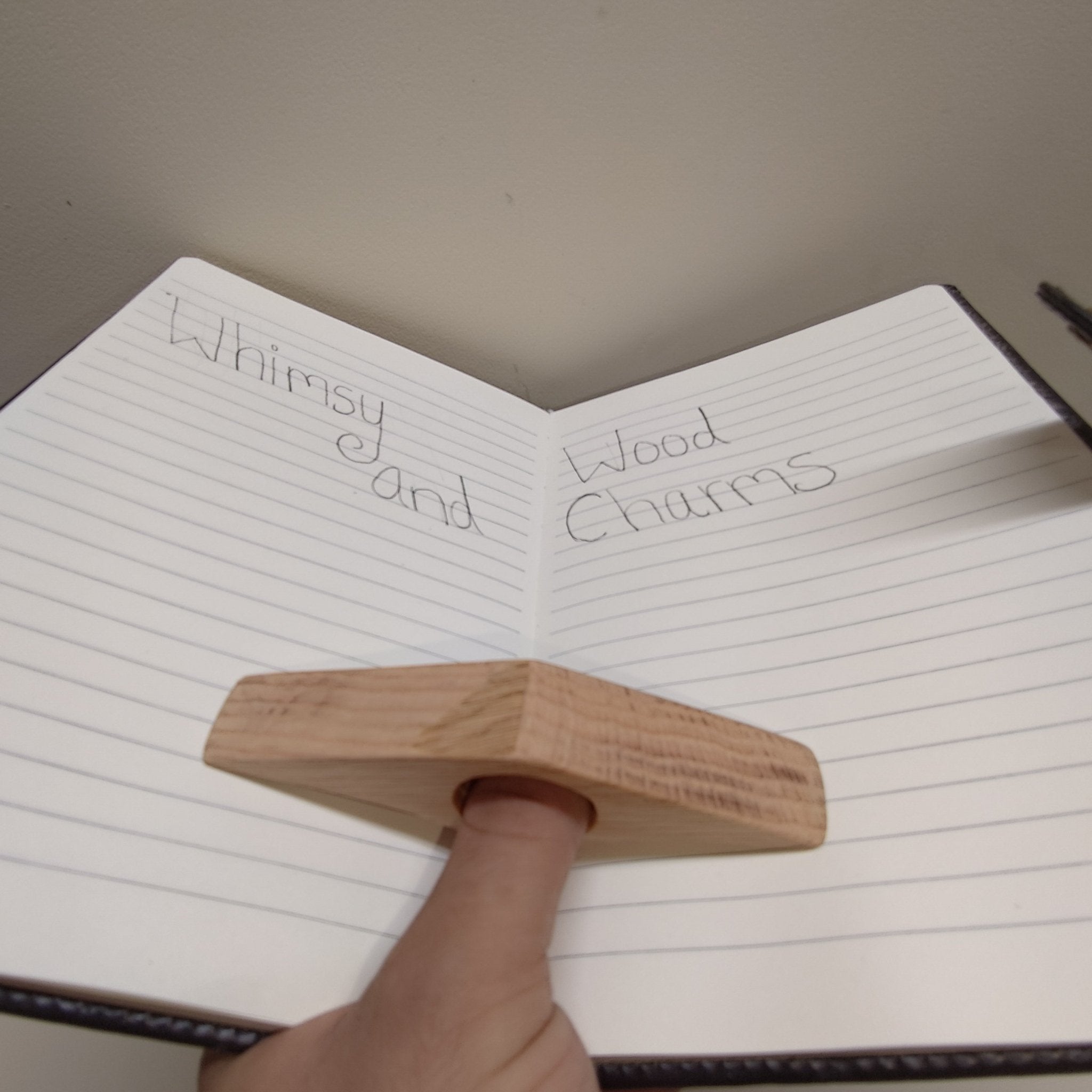 Red oak page holder held over notebook: star-shaped light wood with round hole